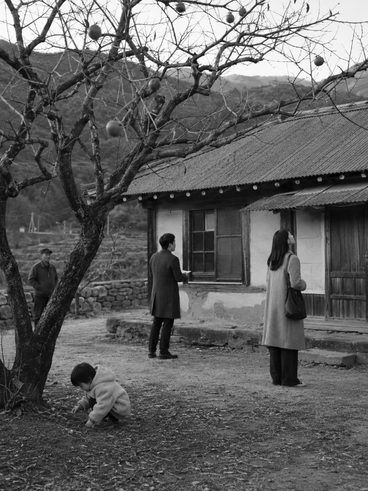 빈집과 감나무를 둘러보는 젊은 부부와 어린아이